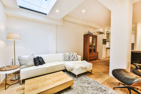 Cozy interior design of living room furnished with comfortable couch and wooden table decorated with...