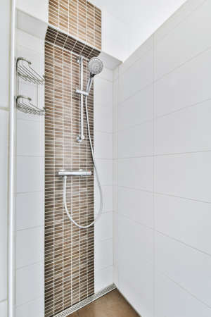 Modern home interior design of light bathroom with white ceramic tiles and bathtub with shower near windowの写真素材