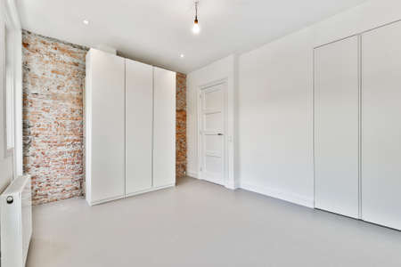 Interior of loft room with minimalist style wardrobe located near balcony doors and windows against...