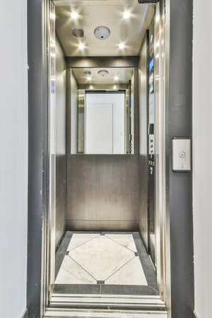Interior of opened elevator with metal doors and mirror in contemporary residential buildingの写真素材