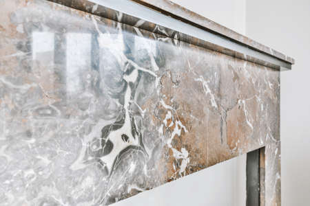 Surface of marble fireplace with reflection of window located in light living room at homeの写真素材