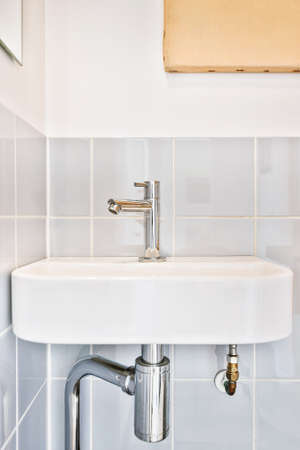 Ceramic sink with faucet located on tiled wall in bathroom of modern apartmentの写真素材