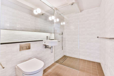 Sink and toilet located in small bathroom with mirror and painting in new apartmentの写真素材