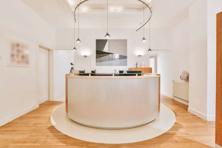 Modern counter illuminated with many lamps located on reception of contemporary officeの写真素材