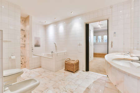 Interior of brightly illuminated restroom decorated with white marble tiles in modern houseの写真素材