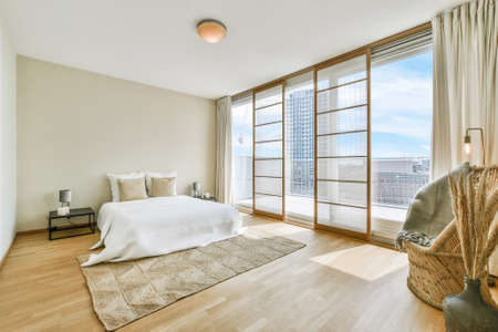 Interior of spacious light bedroom with balcony in contemporary apartment at sunny daytime
