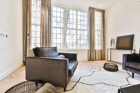 Contemporary cozy armchairs and sofa on soft carpet in light modern living room with minimalist...
