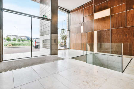 Contemporary interior design of spacious hall with large windows and light marble floor and with geometric wooden wall decorの販売画像