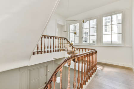 Wooden floor and classic railings of stairway in luxury mansion house with white walls
