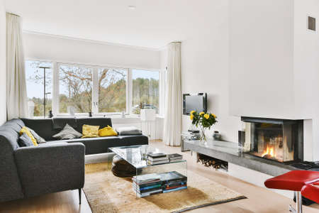 White light living room with L shaped couch with colorful cushions and fireplace with granite shelf...