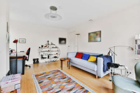 Modern interior of room with gray tiled floor furnished with modern couch and floor lamp under...