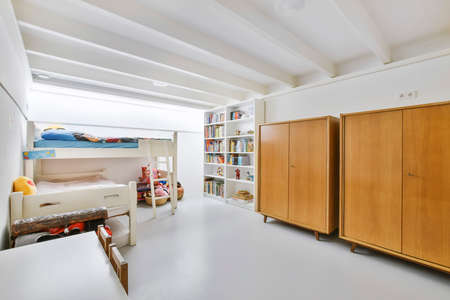 Interior of spacious bedroom with double deck beds and bookshelf with wooden wardrobe