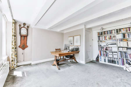 Interior of light house office room with wooden chair and computer against fireplace with corner of...