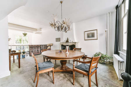 Big cozy room with vintage wooden chairs and table under white beamed ceiling in daylight