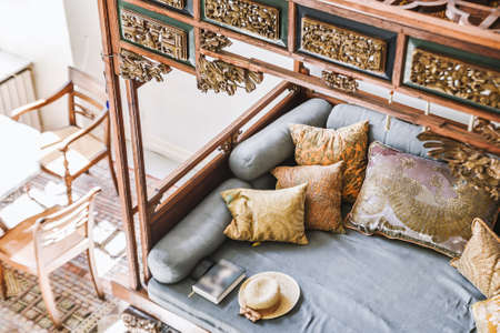 Mirror reflection of old wooden seat with cushions and decorative lanterns in houseの写真素材