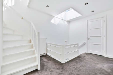 House storey with gray carpet flooring and white elements of staircase and ceiling window
