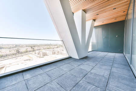 Balcony of luxury apartment in high rise building with glass fence and view of city from height