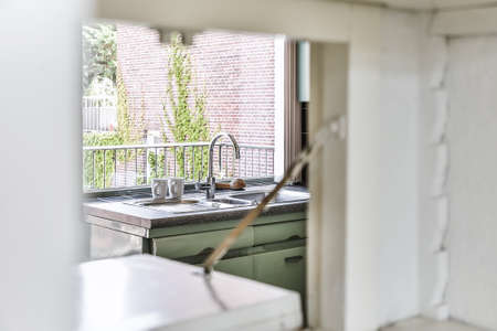 Sink with shiny tap installed under modern counter near jar with spices and gas stove in kitchen at...