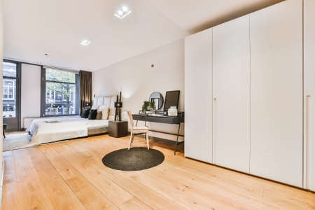 Comfortable bed with blanket and pillows in spacious bedroom in modern apartmentの写真素材