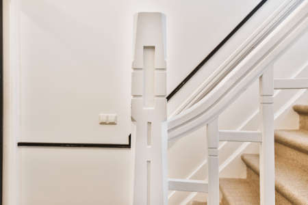 Light narrow hallway with white stairways and fence in house with few storeysの写真素材
