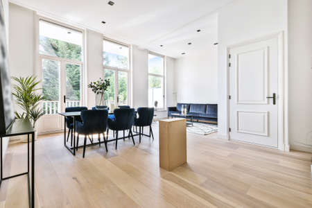 Wooden table with vase and chairs in light dining room at homeの写真素材