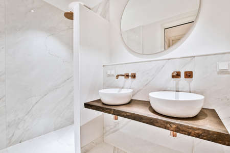 Contemporary interior of bathroom with shower and toilet near white ceramic sinks in flatの写真素材