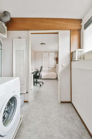 Small room with washing machine and door leading to the bedroomの写真素材