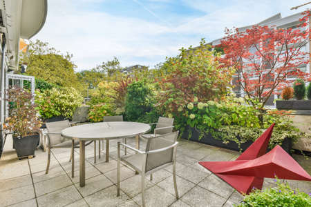 Cozy house courtyard with lots of greenery and modern table and chairsの写真素材