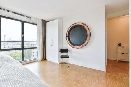 Sunlit bed covered with blanket in light contemporary bedroomの写真素材