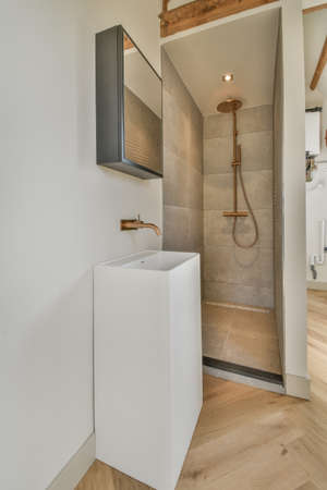 Stylish wash basin with large round mirror and walk-in shower nearbyの写真素材