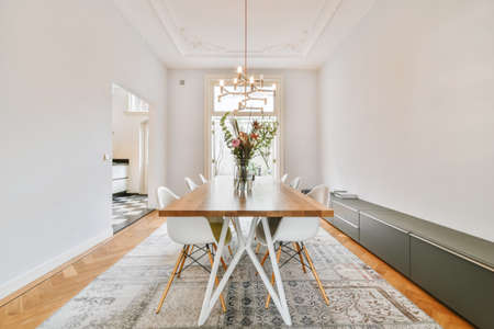 Spacious dining room with table and chairs in modern apartment in minimal style