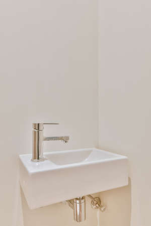 Luxurious washroom with beige tiled floor and miniature washbasinの写真素材