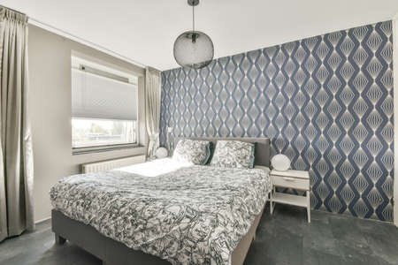 Luxury bedroom in gray tones with a bed covered with a patterned bedspreadの写真素材