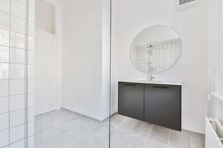 Delightful sink with faucet in front of round mirrorの写真素材