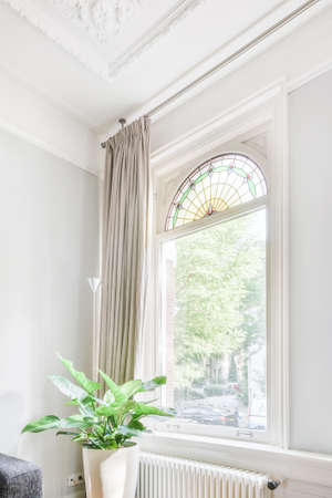 View of a beautiful window with a curtain and a flower nearbyの写真素材