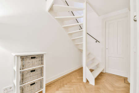 White hallway with wooden stairway leading to second floor of modern luxury apartment with minimalist interior designの写真素材