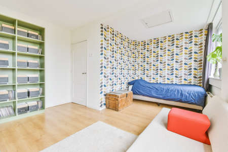 Bedroom with unusual colorful wallpaper and a large green wardrobe with shelvesの写真素材