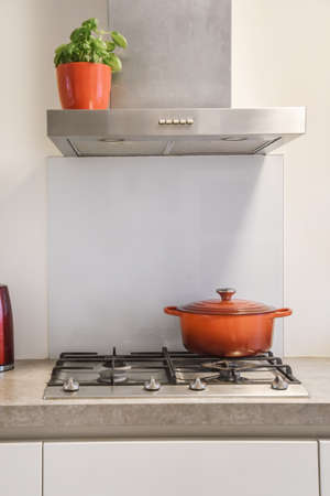 Cozy kitchen in daylight with gas hob and bright red ceramic saucepanの写真素材