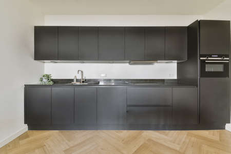 Black all-wall kitchen set in modern kitchen with parquet floorの写真素材