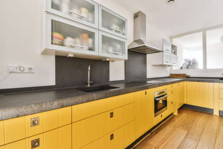 Pretty kitchen with yellow kitchen unit and hanging cabinets with frosted glass
