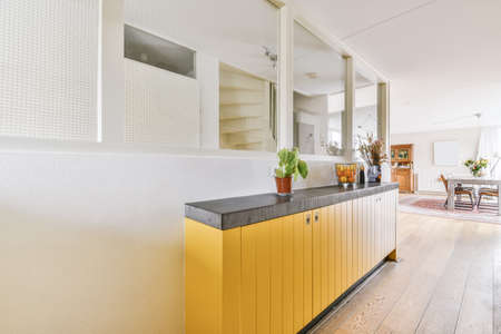 A lovely corridor with a yellow cabinet and a flower in a pot