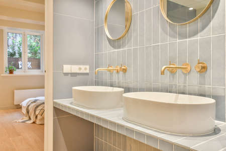 Sink with tap and liquid soap under mirror in contemporary restroom at home