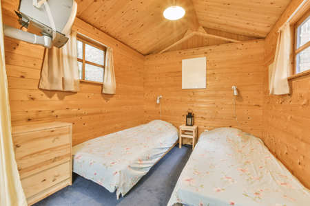 Cozy room with wooden walls and ceiling and two bedsの写真素材