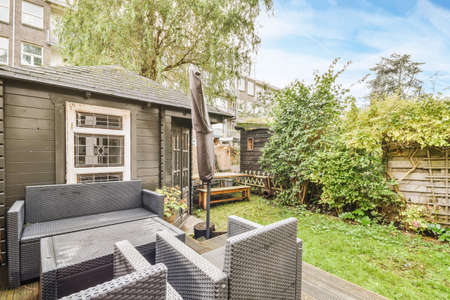 Cozy courtyard of the house with a fresh lawn and a black adjoining house