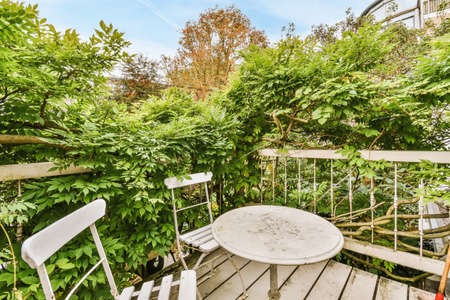 Amazing balcony with green tree braided railings and a table with chairsの写真素材
