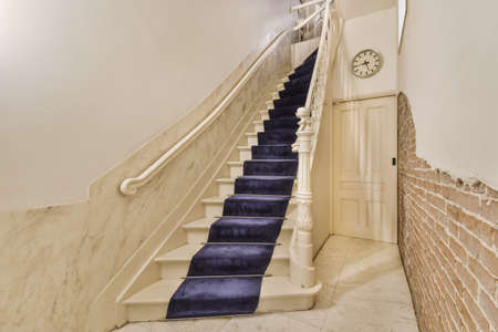 White hallway with wooden stairway leading to second floor of modern luxury apartment with...