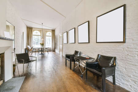 Cozy living room with black leather armchairs and paintings on the walls