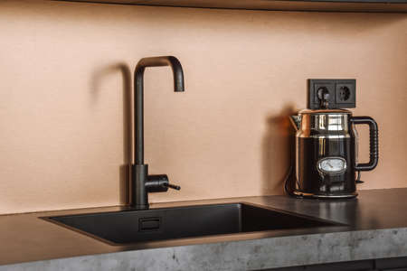 Amazing black sink beside vintage black teapot in kitchen