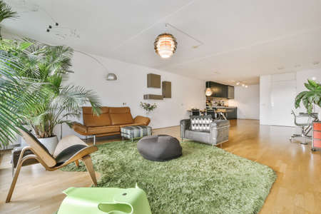 Cozy and stylish living room with green carpet near sofas and ottomansの写真素材