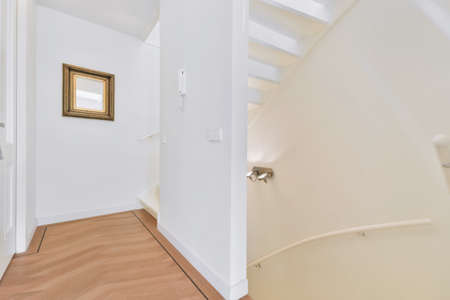 An empty corridor with a staircase and a small mirror on the wall